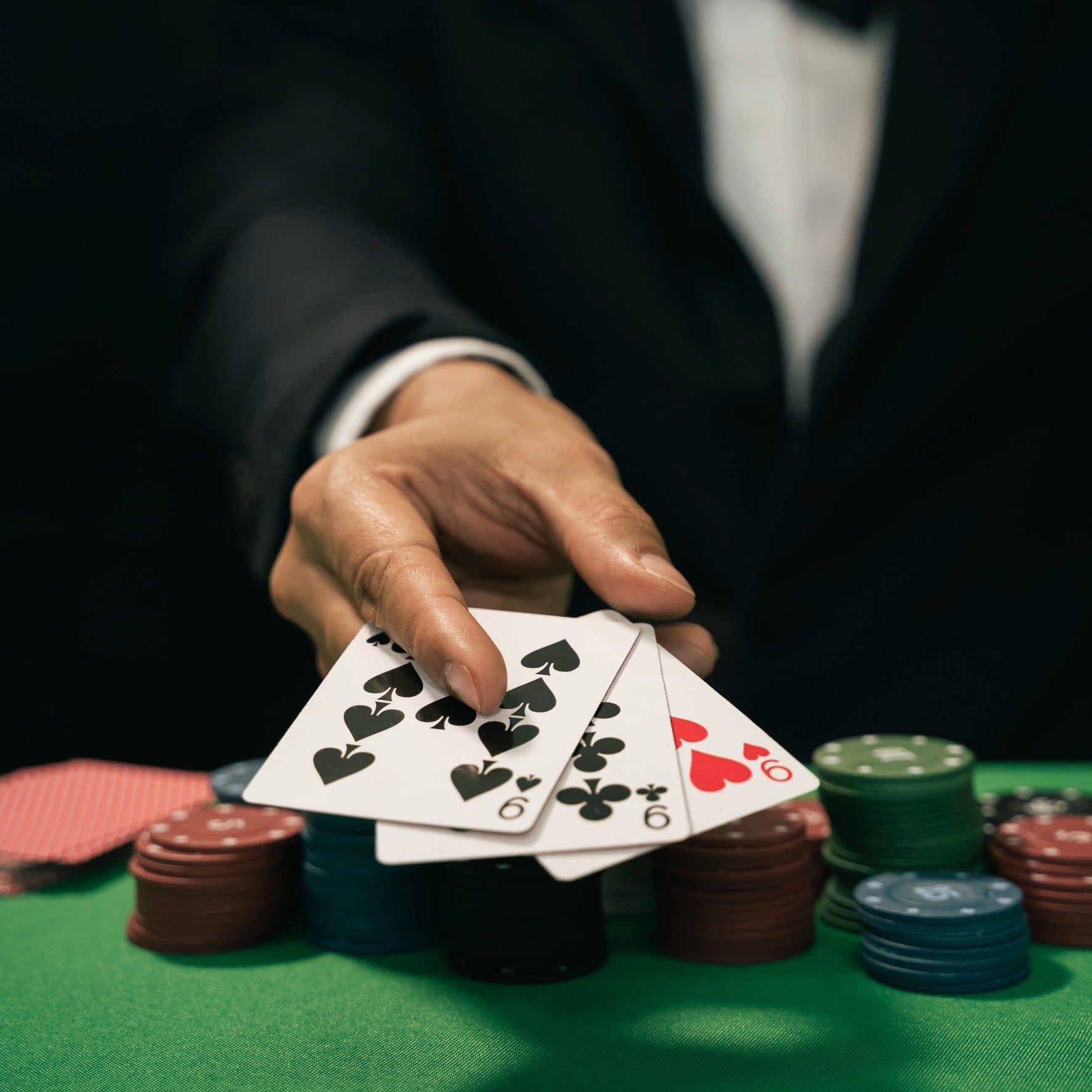 Croupier legt Spielkarten neben gestapelten Jetons auf den grünen Tisch
