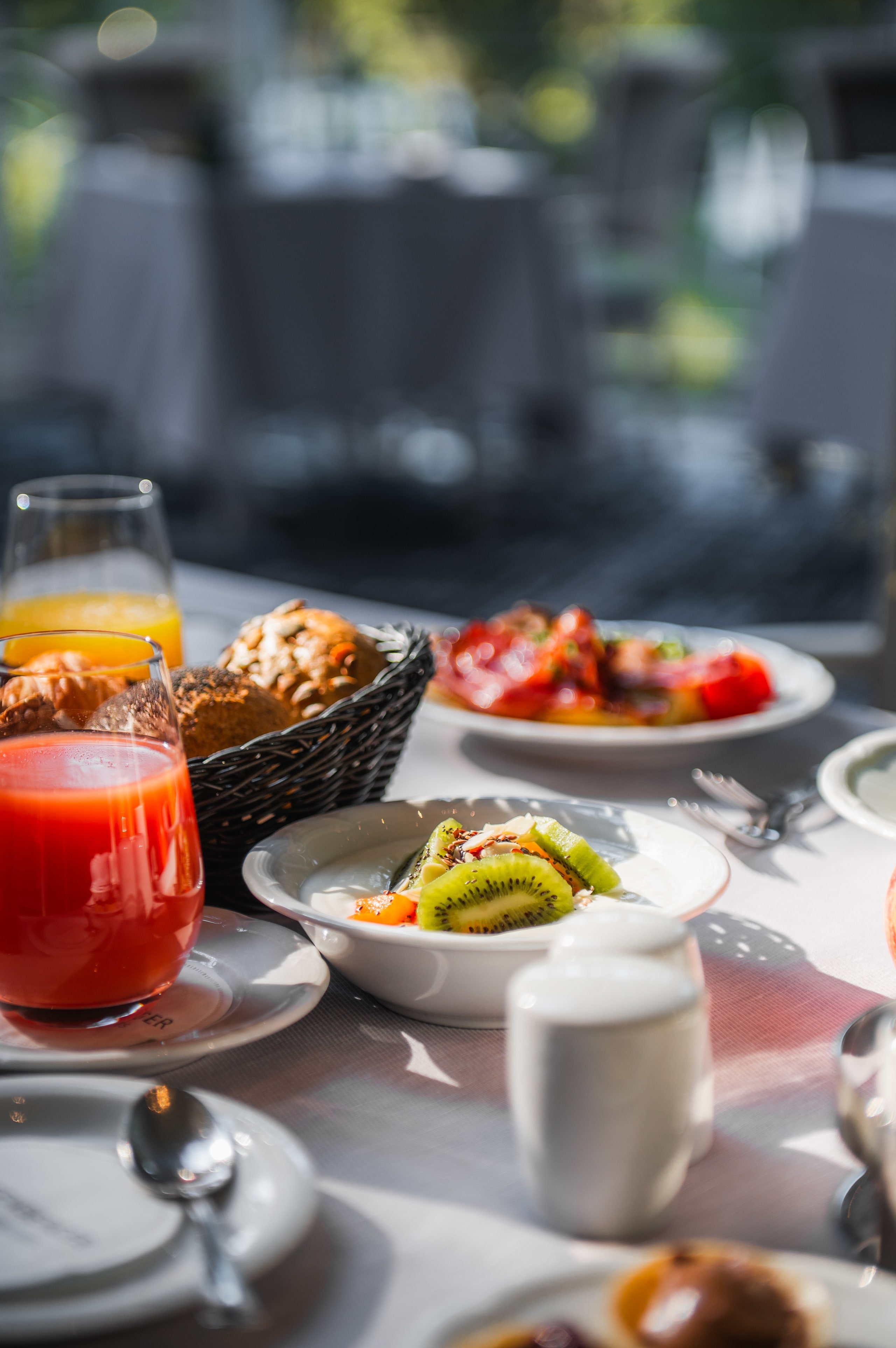Gedeckter Frühstückstisch mit frisch gepresstem Saft, Obst und Gebäck