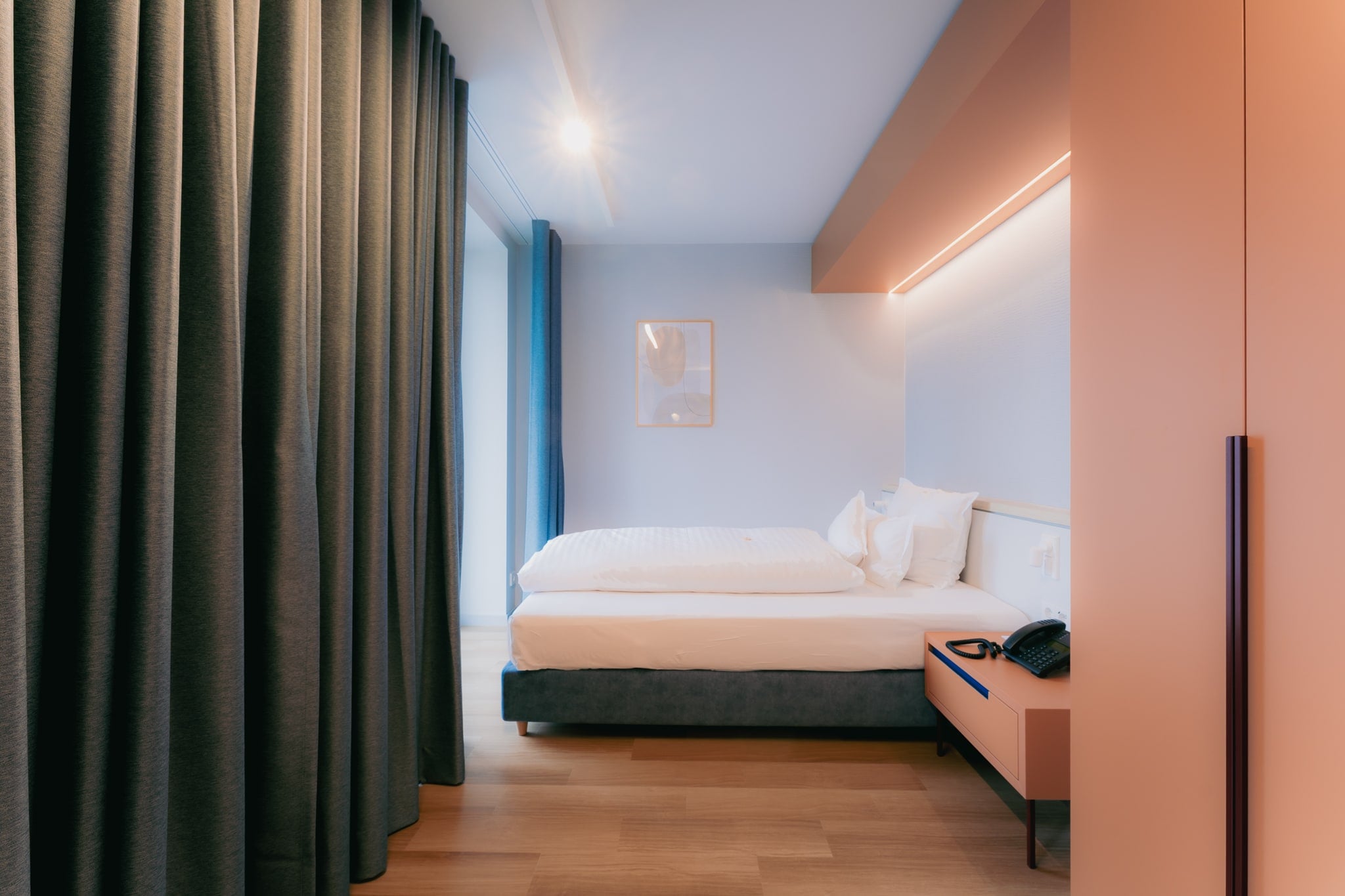 Zimmer mit Doppelbett, warmem Nachtlicht und bodentiefem Vorhang