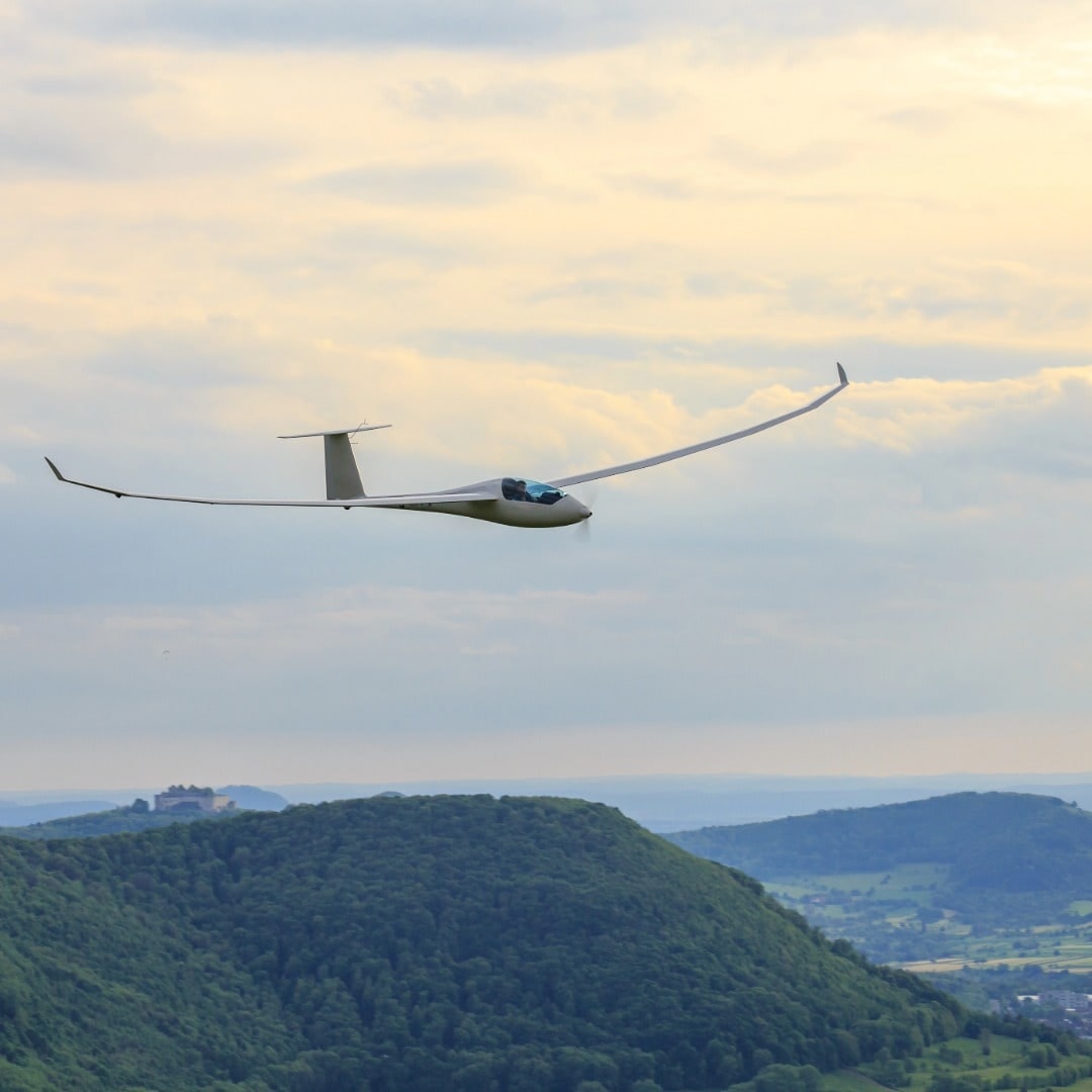 Segelflugzeug über den Hügeln des Allgäus im Abendlicht